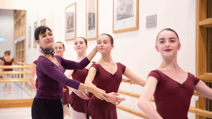 Four Upper School girls working with their teacher at the barre