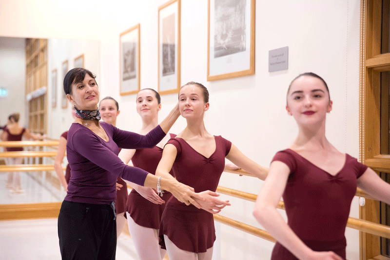 Four upper school girls working with their teacher at the barre