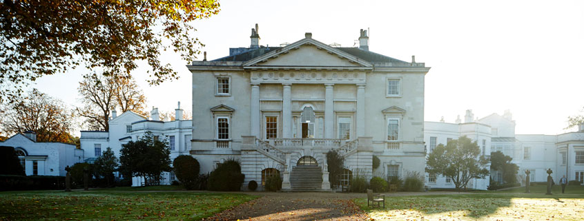 The exterior of white lodge, a grand white building, in autumn sunlight.