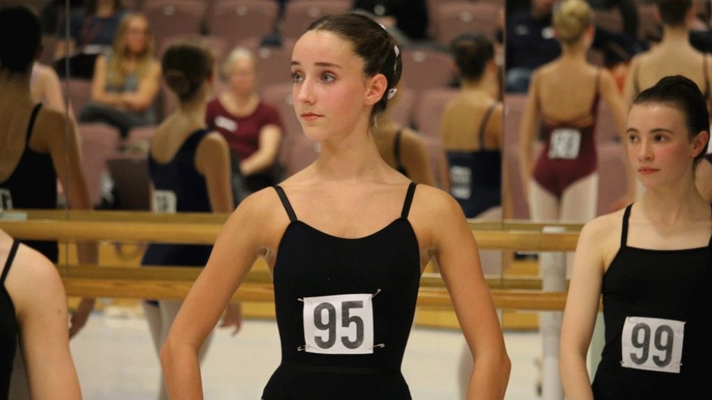 Student in black leotard with a number on her chest standing in an audition