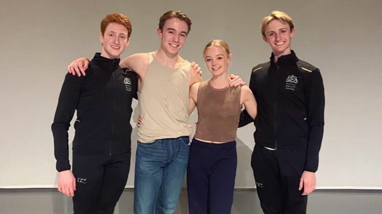 Four student choreographers standing together and smiling at the camera