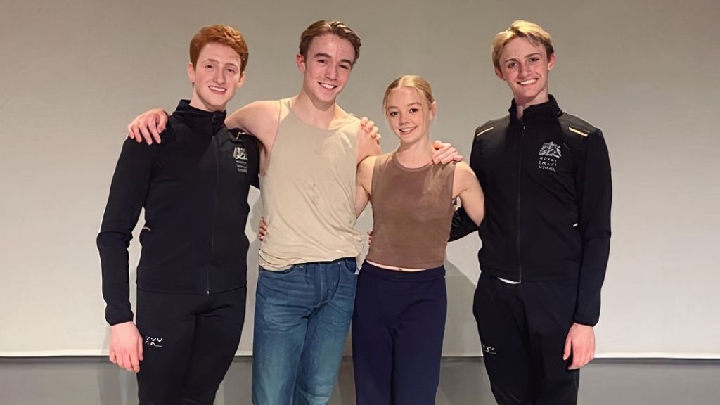 Four student choreographers standing together and smiling at the camera