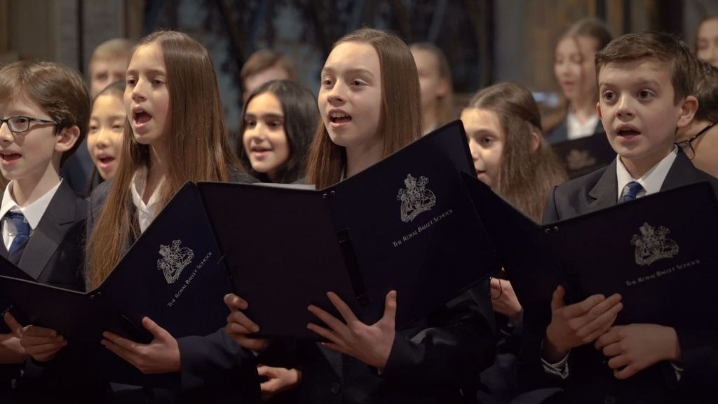 Children in a choir sing from choirbooks