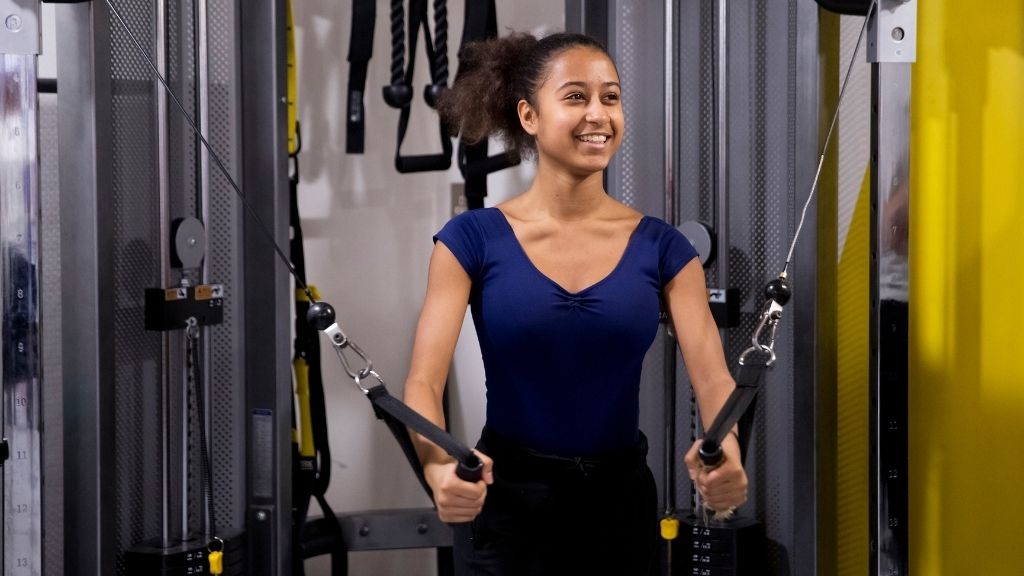 A female dancer uses a strengthening machine