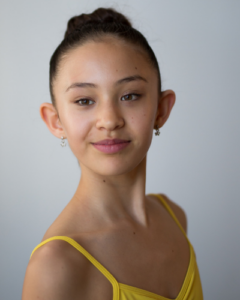 Headshot of lauren wycherley in yellow leotard smiling at the camera