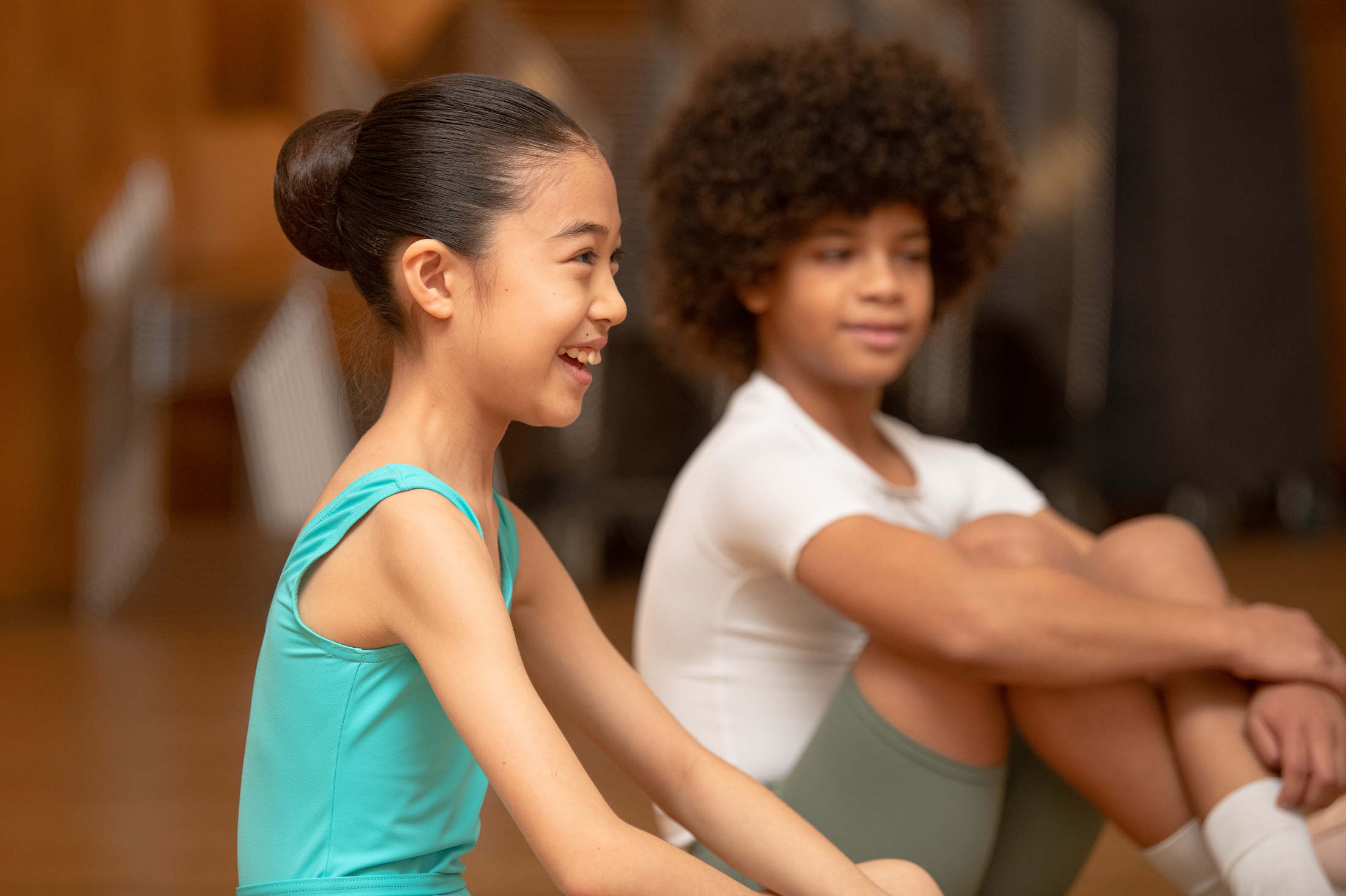 Two students sit on the floor smiling