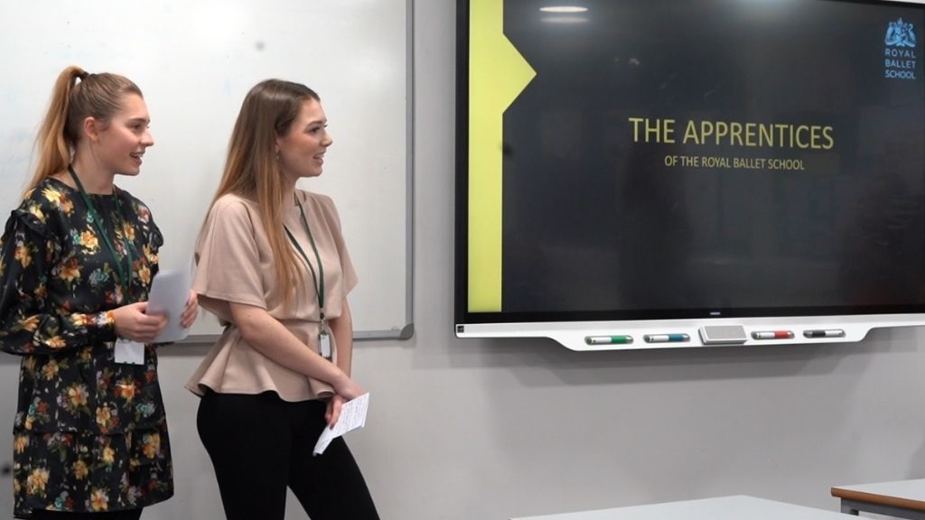 Two apprentices present a powerpoint at the front of a classroom.