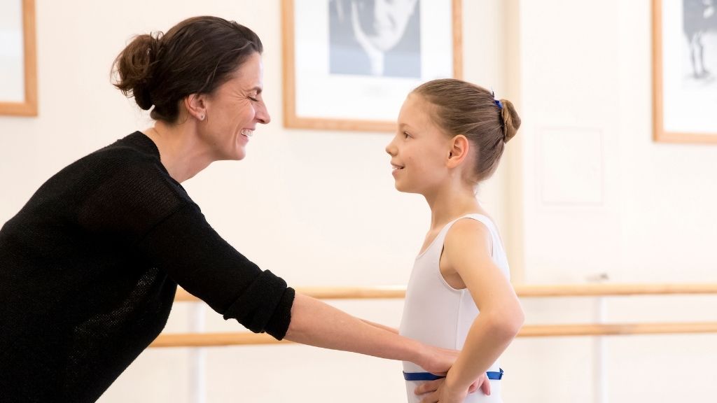 A student and ballet teacher smile at each other