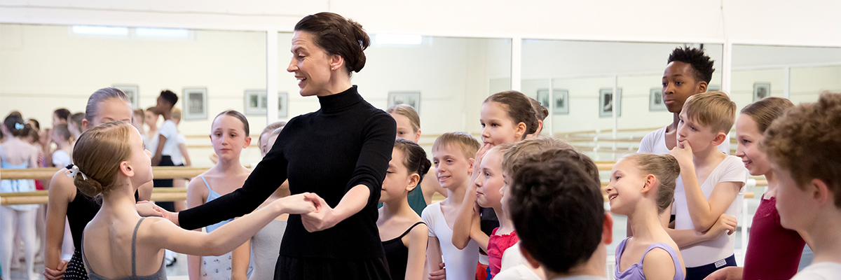 Teacher dancing with student with class watching