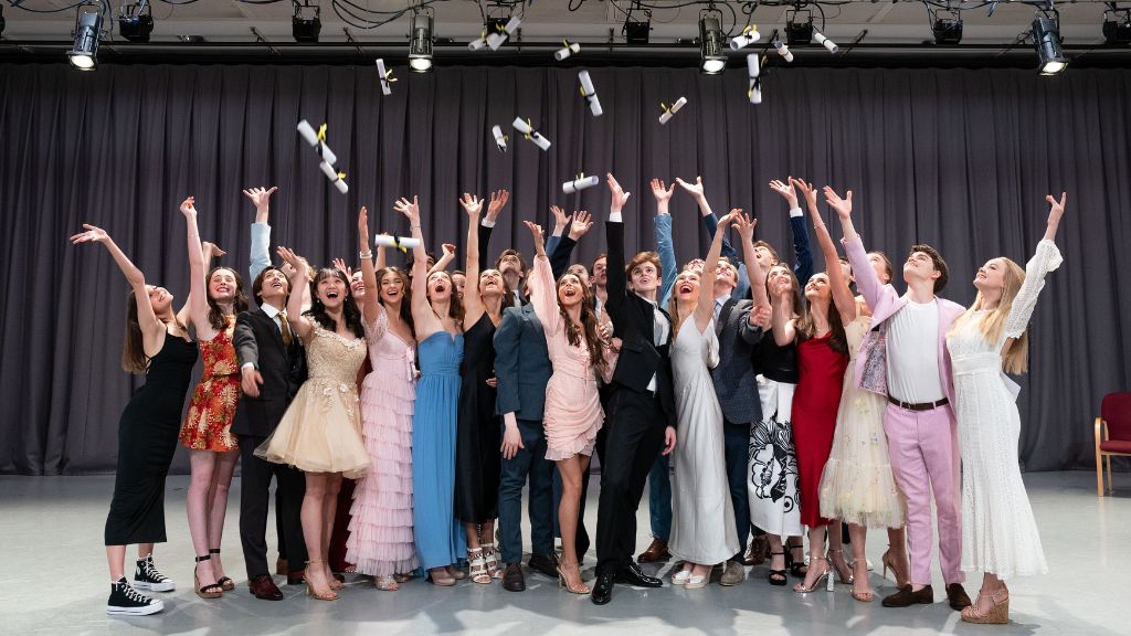 Graduating students throw their diplomas into the air