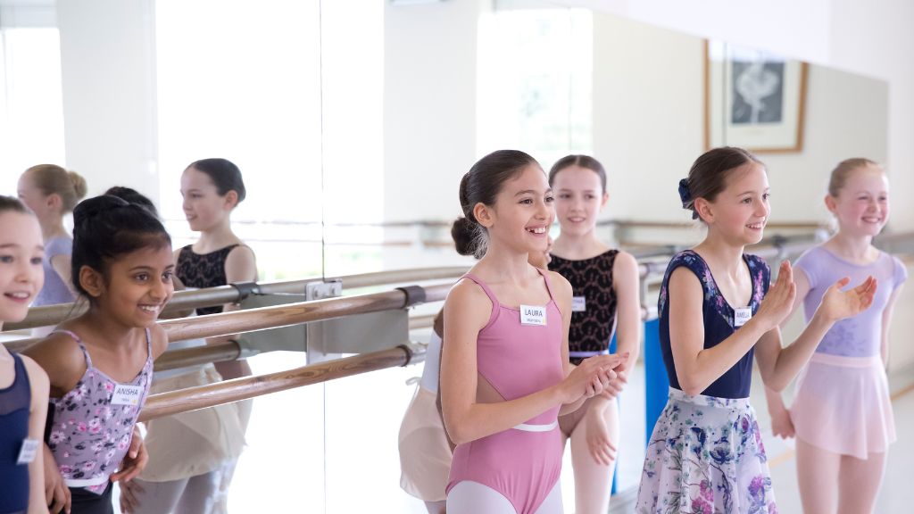 Students stand in front of the barre, smiling and clapping