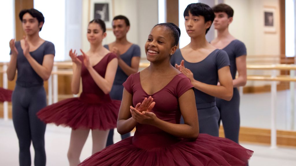 Dancers smile and applaud in a studio