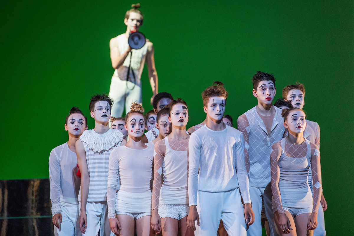 Behind the choreography: didy veldman’s toot Cast of dancers dressed in white clown costumes on stage being commanded by a male clown dancer with a microphone