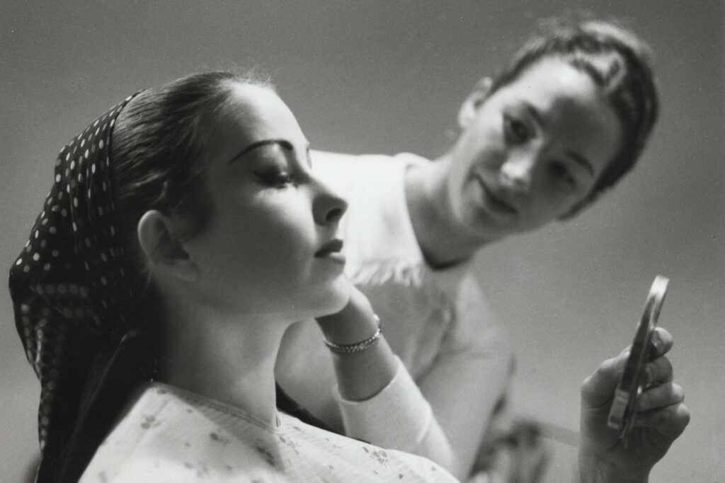 Barbara fewster teaching a student to apply makeup in the 1960s