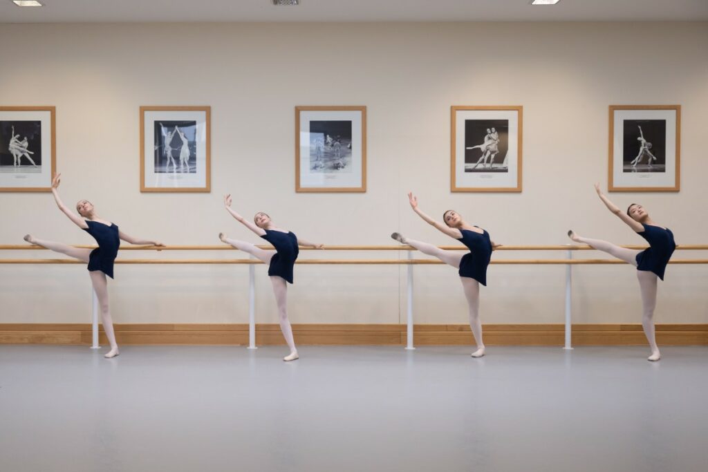 Four female students in ballet class at the barre