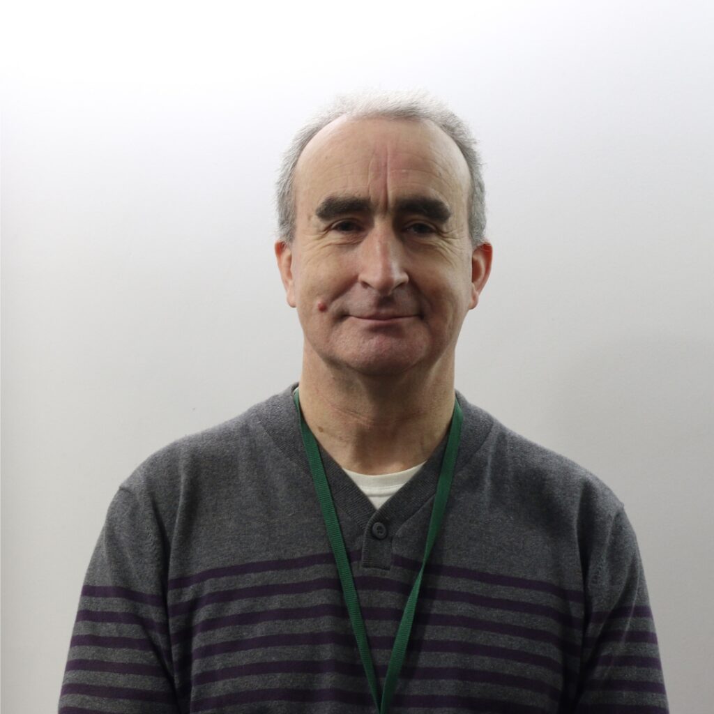 Ray wheaton headshot wearing a grey jumper with black stripes