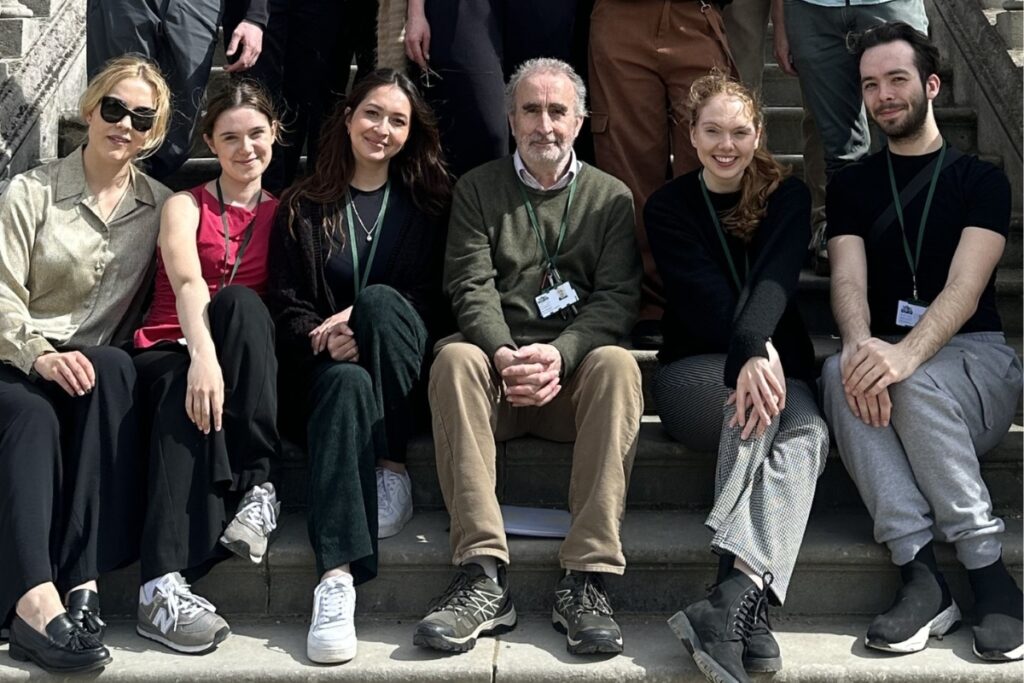 Ray wheaton sitting on the steps of white lodge surrounded by summer intensive pastoral staff