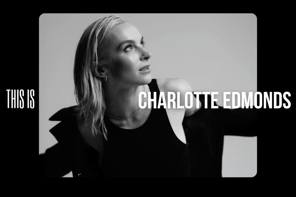 Black and white photograph of charlotte edmonds looking up, wearing a black tank top and blazer.