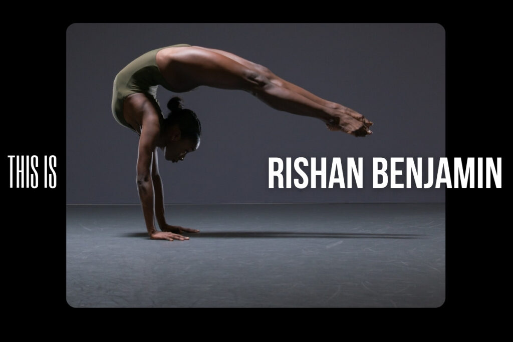 Rishan benjamin wearing an olive green leotard balancing upside-down on her hands with her back arched and legs pointing down to the floor
