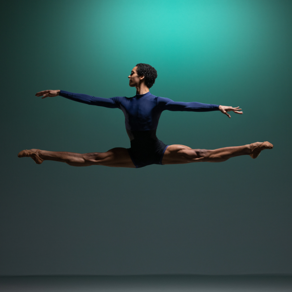 Davi doing the splits in the air in a blue costume.