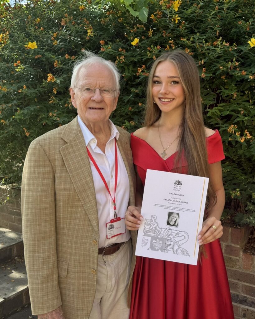 Three longtime supporters of the school share why they choose to leave a lasting legacy for our students Nigel stands with award winner nika. Nigel wears a beige coat and trousers with a white button down shirt. Nika wears a read off-the-shoulder gown with her long light brown hair falling straight down.