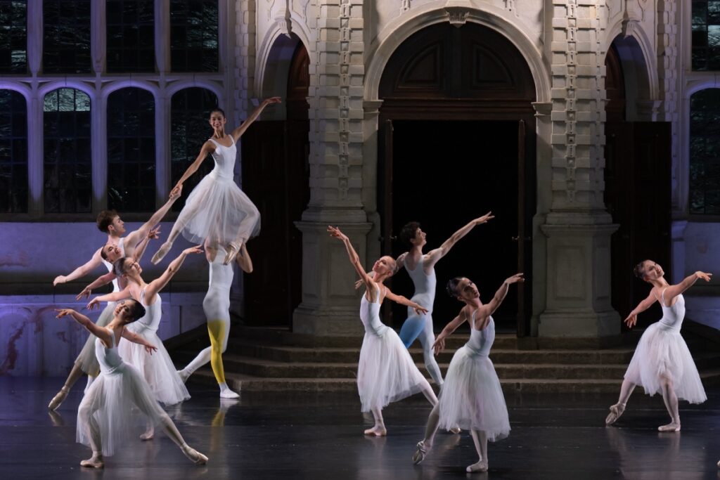 Three longtime supporters of the school share why they choose to leave a lasting legacy for our students Dancers dressed in white leotards, tulle skirts and tights with splashes of pastel colour dance in different poses on the opera holland park stage. One female dancer is lifted high into the air, with her left upstage arm raised to the front and her gaze lifted.
