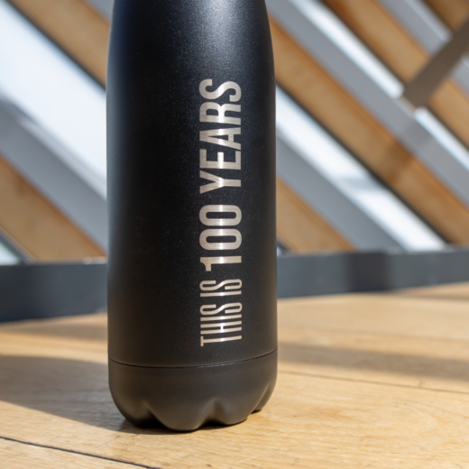 Black centenary water bottle from The Royal Ballet School, with text 'this is 100 years'.