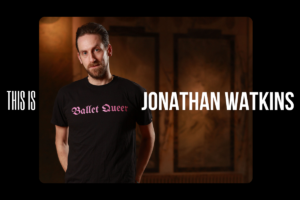 Jonathan standing in a black t-shirt that has his dance company 'ballet queer' written on it in pink.