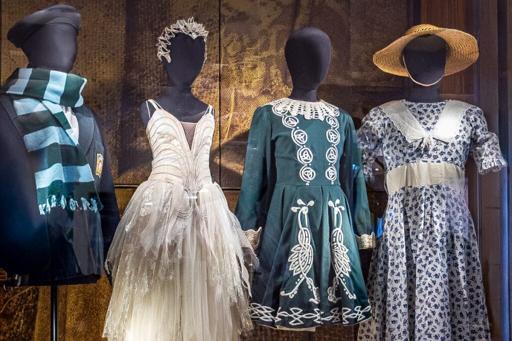 The royal opera house opens part one of the royal ballet school’s centenary exhibition, designed by exhibitions curator robin footitt Four black mannequins display uniforms and costumes from the past. From left to right: a navy blue blazer with the royal ballet school crest and a scarf wrapped around the neck with light blue and dark green stripes; a little swan dress with a white crown and feather details; a dark green traditional irish dance dress with intricate white patterns running down the front symmetrically; a white dress with a blue floral pattern, a white lace collar and a straw hat.