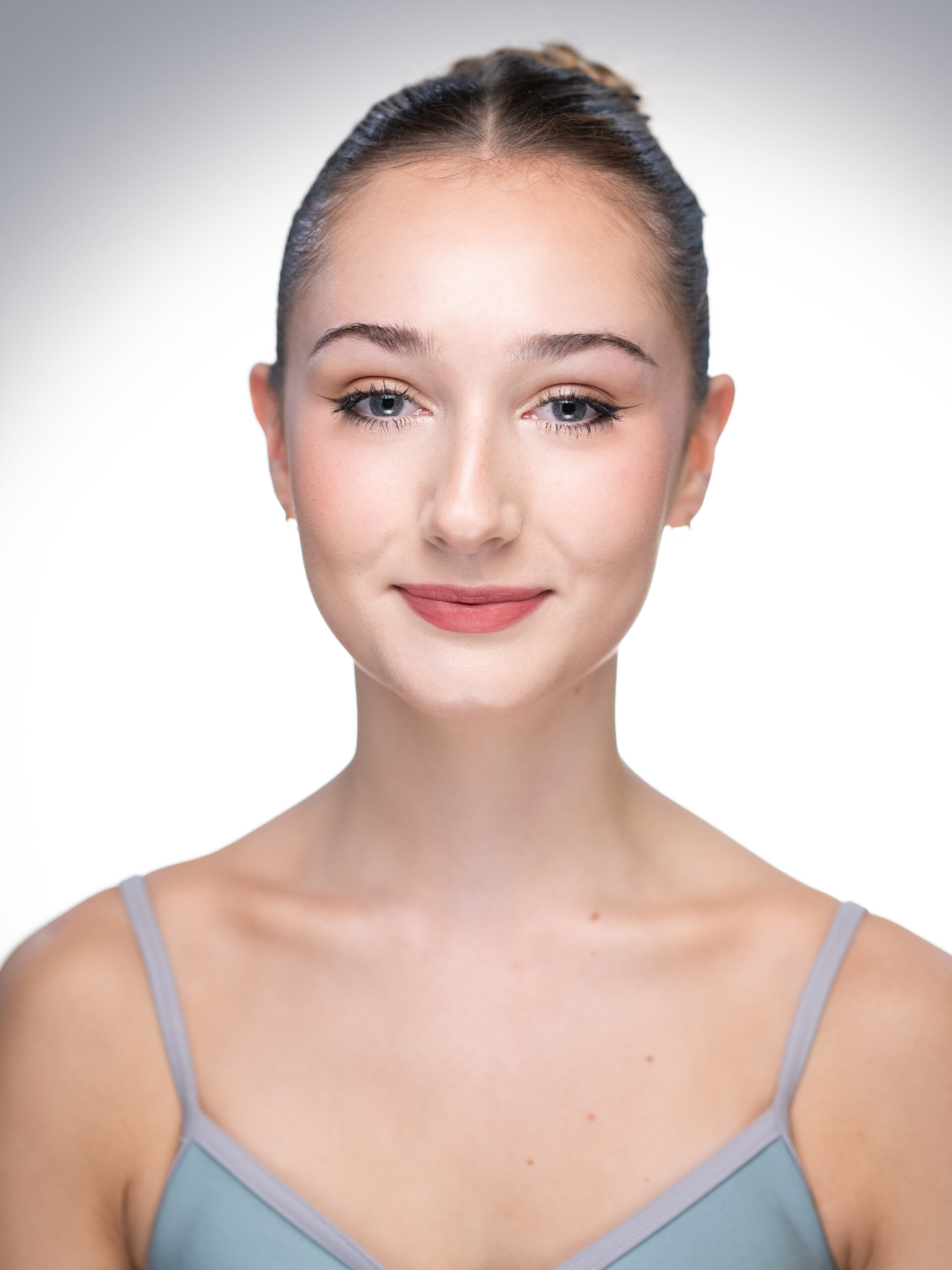 Student choreography shines at benefact group’s service of celebration at st paul's cathedral Layla's headshot - layla wears a light blue spaghetti strap leotard. Her hair is scraped back into a french twist. She wears soft makeup and softly smiles towards the camera.