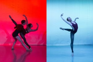 Two photos are side by side. On the left, bright red light illuminates the image. The female dancer is in a diagonal split on pointe, her arms bent above her head. The male dancer bends his left leg and extends his right on the ground while holding the female dancer's waist. He wears a long sleeve black shirt and black shorts. She wears a black strappy leotard and black tights. On the right, icy blue light illuminates the stage. A female dancer is mid-renverse, her left leg in attitude back and her right arm raised in 5th. She wears a black leotard and black tights with skin tone pointe shoes.