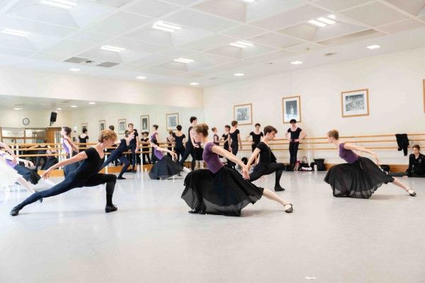 ‘refine all the time:’ alum samara downs on staging checkmate and swan lake for our summer performances Female students in purple leotards and long black skirts with pink tights and black character shoes face male students in black shirts, tights and character shoes in deep lunges. Their arms are slightly curved behind them, following the line of their diagonal torsos and legs.