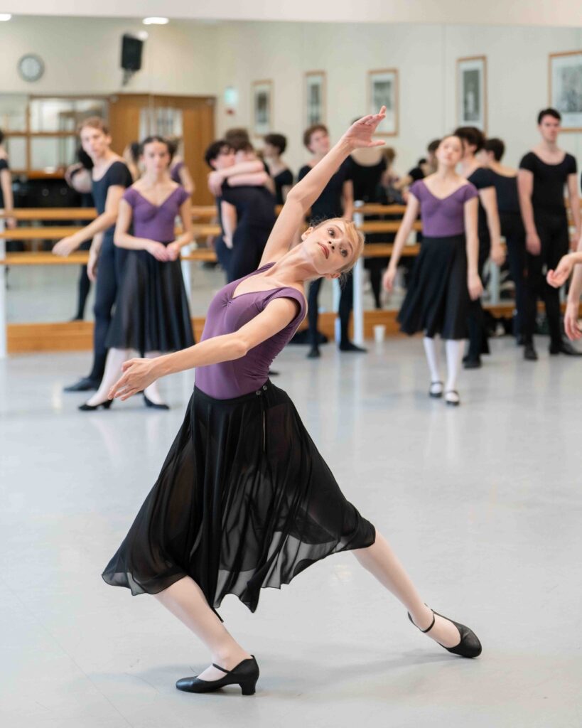 ‘refine all the time:’ alum samara downs on staging checkmate and swan lake for our summer performances A female student in a purple leotard, long black skirt, pink tights and black character shoes lunges with her right leg bent forward and her left leg extended back. Her right arm is raised in fifth position with her left arm curved in first position in front of her. Her back arches and her head is held at a backwards angle.