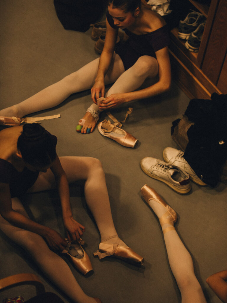 The school takes over covent garden this summer with screenings, sculptures, sweets and more An overhead shot of dancers putting on their pointe shoes with sneakers on the floor nearby. One girl's foot is taped in blue and green bandages