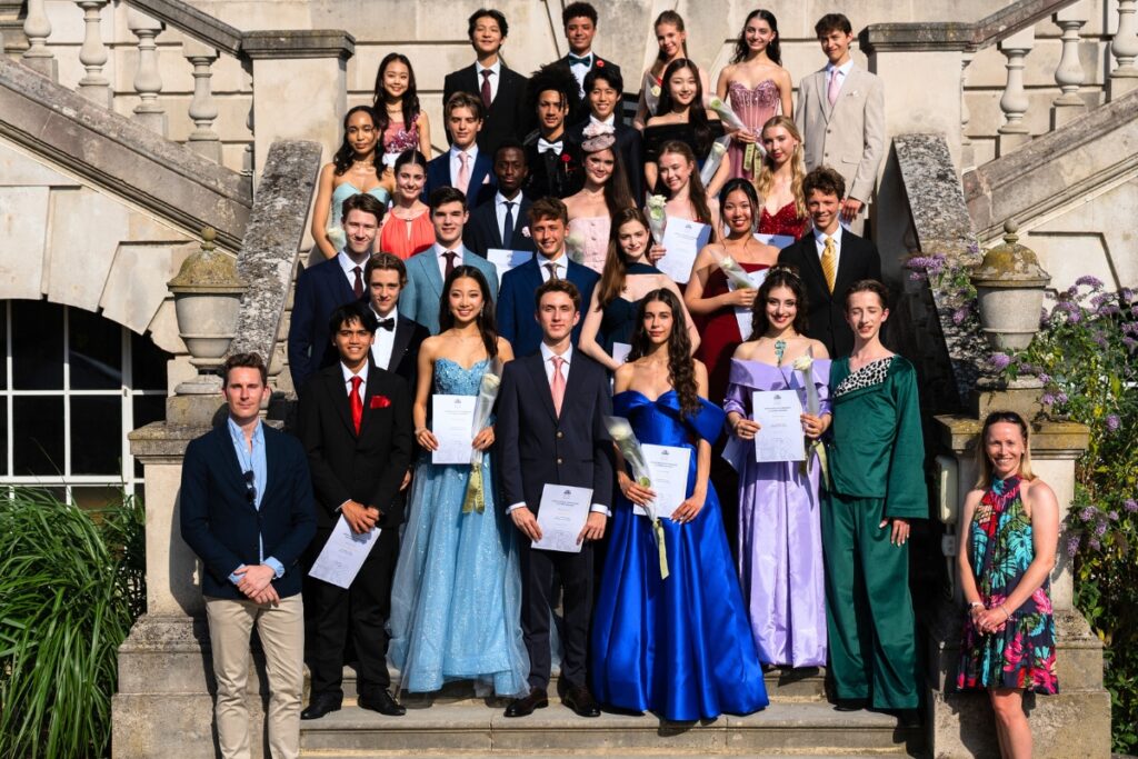 End-of-year celebrations and prize-giving ceremonies 2026 Year 11 students stand in a group on the stairs of white lodge in multicoloured gowns and suits.