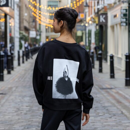 Product image of 'Centenary rehearsal sweatshirt' in black. Worn by a Royal Ballet School student in Upper School, Covent Garden. A collection of merchandise in celebration of 100 years of The Royal Ballet School.