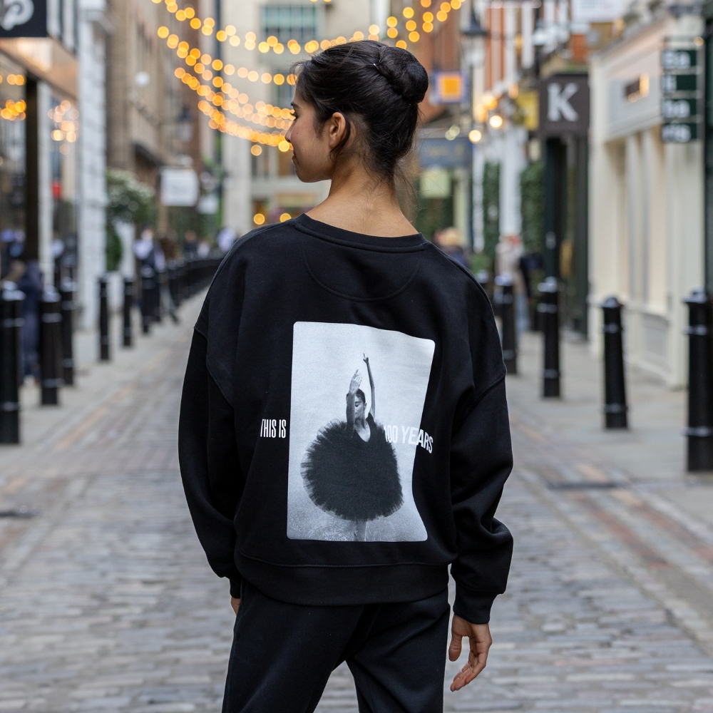 Tutu centenary cropped sweatshirt Product image of 'centenary rehearsal sweatshirt' in black. Worn by a royal ballet school student in upper school, covent garden. A collection of merchandise in celebration of 100 years of the royal ballet school.
