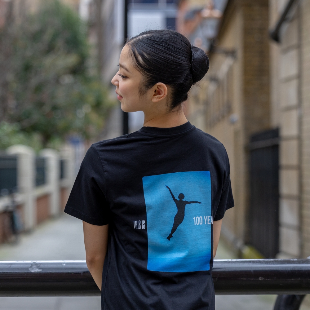 Bluebird centenary children's t-shirt Product image of 'centenary performance children's t-shirt' in black. Worn by a royal ballet school student in upper school, covent garden. A collection of merchandise in celebration of 100 years of the royal ballet school.