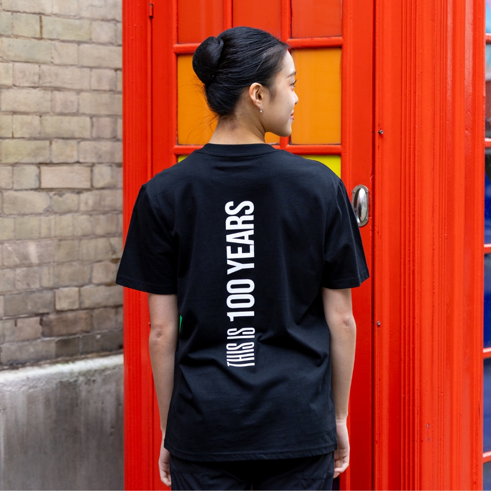 This is 100 years t-shirt black Product image of 'this is 100 years t-shirt' in black. Worn by a royal ballet school student in upper school, covent garden. A collection of merchandise in celebration of 100 years of the royal ballet school.