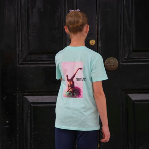 Product image of 'Centenary performance children's t-shirt' in mint. Worn by a Royal Ballet School student at White Lodge. A collection of merchandise in celebration of 100 years of The Royal Ballet School.