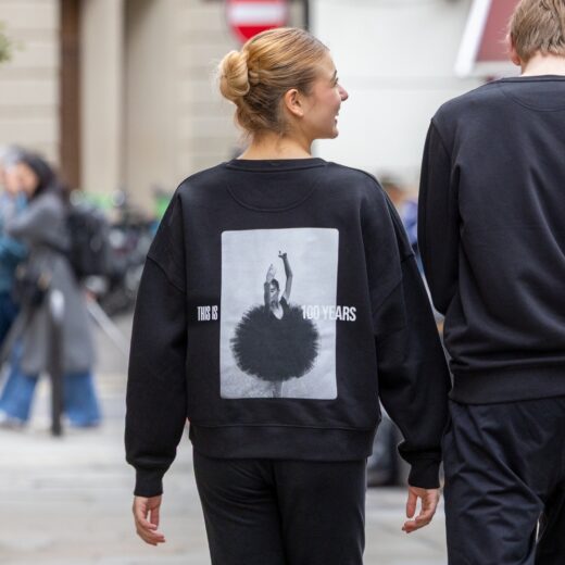 Product image of 'Centenary rehearsal sweatshirt' in black. Worn by a Royal Ballet School student in Upper School, Covent Garden. A collection of merchandise in celebration of 100 years of The Royal Ballet School.