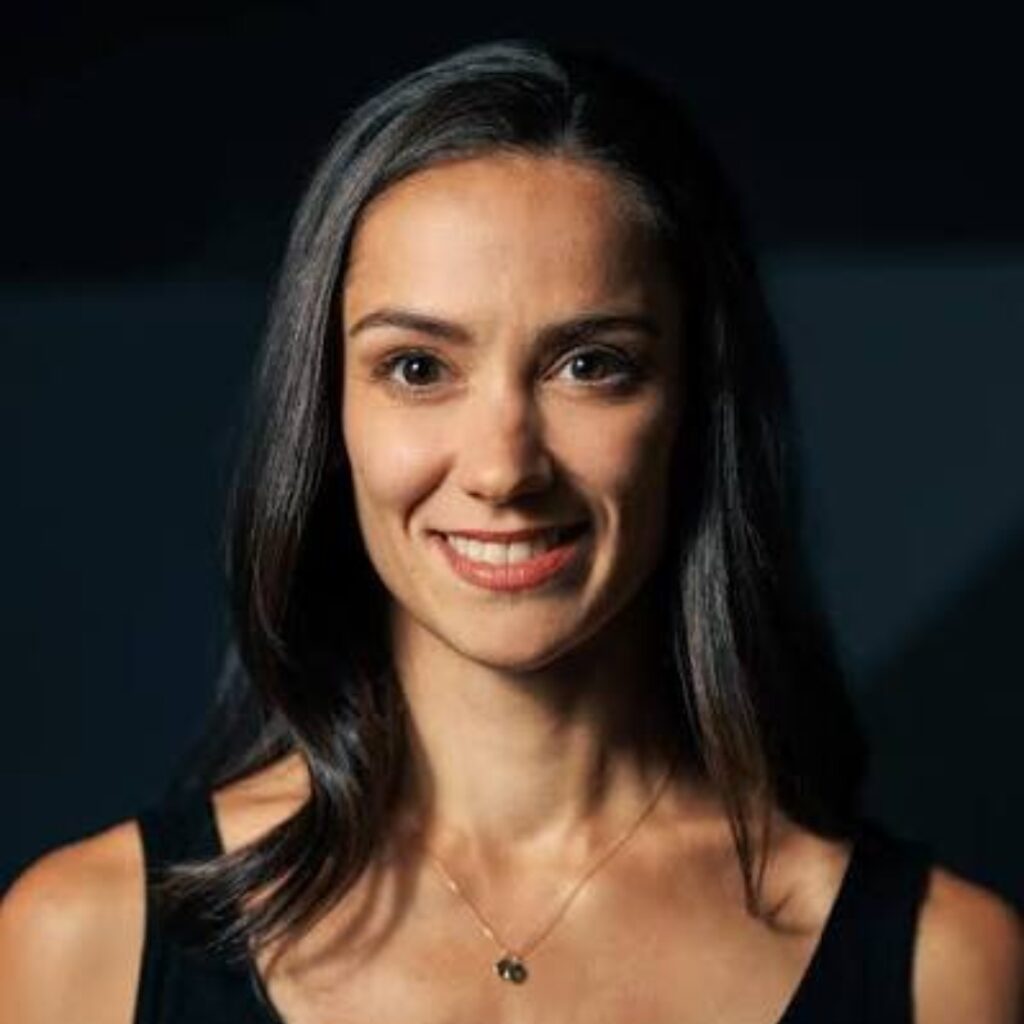 Sophie smiles at the camera with her black straight hair falling to her collarbone. She wears a black tank top.