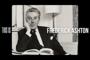 Frederick ashton looks at the camera, propping his chin in his right hand.