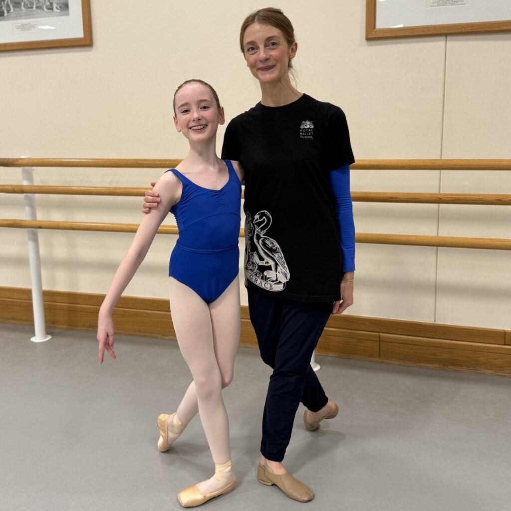 Mid associate students share what they love about the associate programme Lydia stands in b+ position in a blue leotard standing next to amber doyle in the studio.