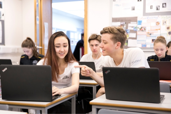 A day in the life of a full-time student at the royal ballet school Two upper school students sit in a classroom looking at laptops. A boy leans over to point at a girl's screen.